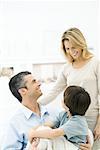 Family smiling at each other, boy sitting on father's lap