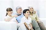 Multi-generation family sitting together on sofa, watching TV