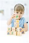 Little girl stacking blocks, focus on foreground