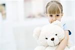 Little girl holding teddy bear, portrait