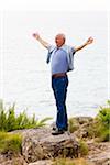 Man Standing on Cliff Looking Out at Ocean