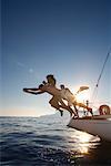 Group dive off back of sailboat