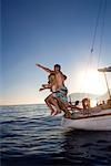 Young people jumping from sail boat