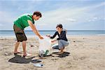 Young couple collecting garbage on beach