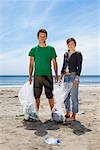 Young couple collecting garbage on beach