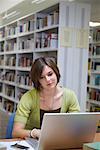 Junge Frau, die Arbeiten am Laptop in der Bibliothek