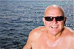 Portrait of Man Sitting by Lake, Wearing Sunglasses