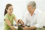 Grandfather holding vinyl record, granddaughter pointing