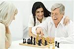 Senior couple jouant aux échecs, fille adulte assis avec bras autour de père