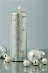 Silver advent candle surrounded by Christmas tree ornaments