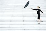 Businesswoman struggling with umbrella in wind