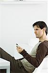 Man holding remote control, sitting and looking away