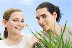 Young man and preteen girl with flowering aloe plant, smiling at camera