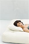 Woman reclining on futon, head on pillow, eyes closed