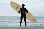 Homme tenant un planche de surf sur la plage