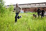 Police Officers and Police Dog Chasing Suspect Through Field