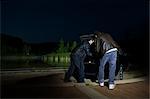 Men Removing Something From Car Trunk at Night