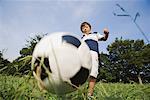 Garçon jouant au football dans le parc