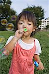 Girl blowing soap bubbles in park