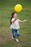 Jeune fille souriante, jouer avec le ballon dans le parc