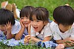 Smiling children lying on front together in park