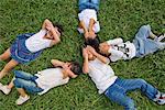Children lying on grass hiding their faces