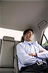 Businessman asleep in backseat of car