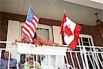 Altes Paar auf Front Porch mit amerikanischen und kanadischen Flaggen