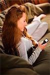 Woman Relaxing on Couch, Listening to MP3 Player