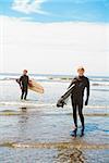 Surfers holding surfboards on the beach, Washington State, USA