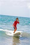 Girl surfing in the sea and talking on a mobile phone