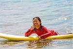 Girl lying on a surfboard and talking on a mobile phone