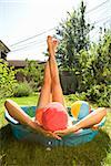 Woman lying in a wading pool with her feet up