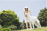 Smiling young woman with white dog in park