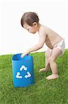 Enfant en bas âge met ses mains dans le bac de recyclage