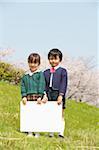 Two Japanese children holding white cardboard