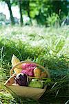 Panier en bois de légumes sur le sol, l'herbe et les arbres en arrière-plan