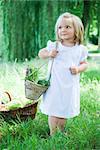 Little girl holding basket of vegetables, looking away