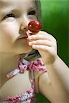 Little girl smelling ripe cherry