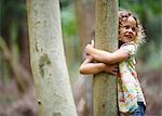 Young girl hugging tree smiling