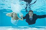 Bride and groom swimming underwater