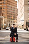 Businessman Sitting on Gas Can in the Middle of a City street