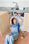 A young woman repairing a sink