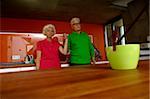 Senior couple holding hands standing in domestic kitchen