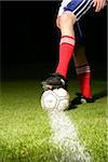 Jeune homme debout avec un pied sur un ballon de football, prêt à marquer (partie de)