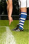 Young footballer stretching his arms down to his feet (part of), selective focus