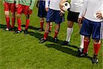 Six footballers in sports wear standing next to each other on a pitch (part of)