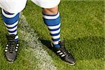 Jambes d'un joueur de football avec le bleu et blanc rayé bas (partie de), gros plan