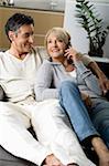 Couple sitting on a sofa while phoning