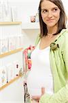 Pregnant woman standing in front of shelf with greeting cards, touching her belly